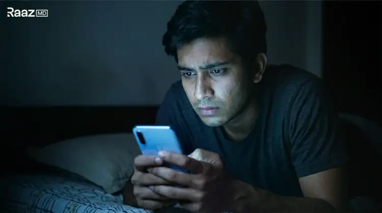 अंधेरे में फोन देखता चिंतित युवक - इंटरनेट पर शीघ्रपतन की गलत जानकारी